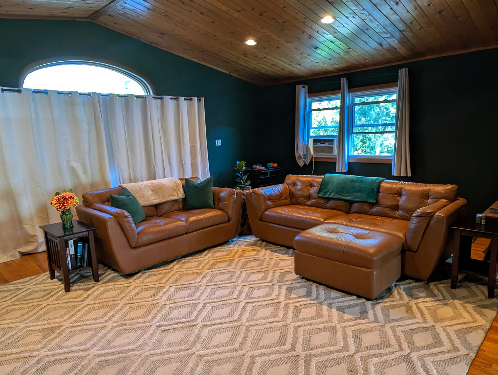 A living room after a clean: leather sofas, a wood ceiling and a clear floor.
